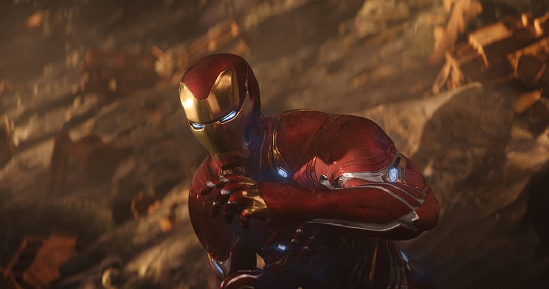 Iron Man en armure rouge et or brillante sur la planète désolée de Titan, avec des roches et débris rocheux en arrière-plan éclairés par une lumière chaude
