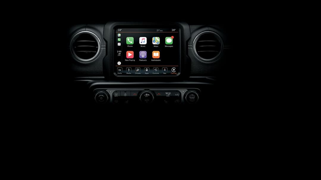 Tableau de bord de la Jeep Wrangler avec écran tactile Uconnect affichant applications et commandes de climatisation