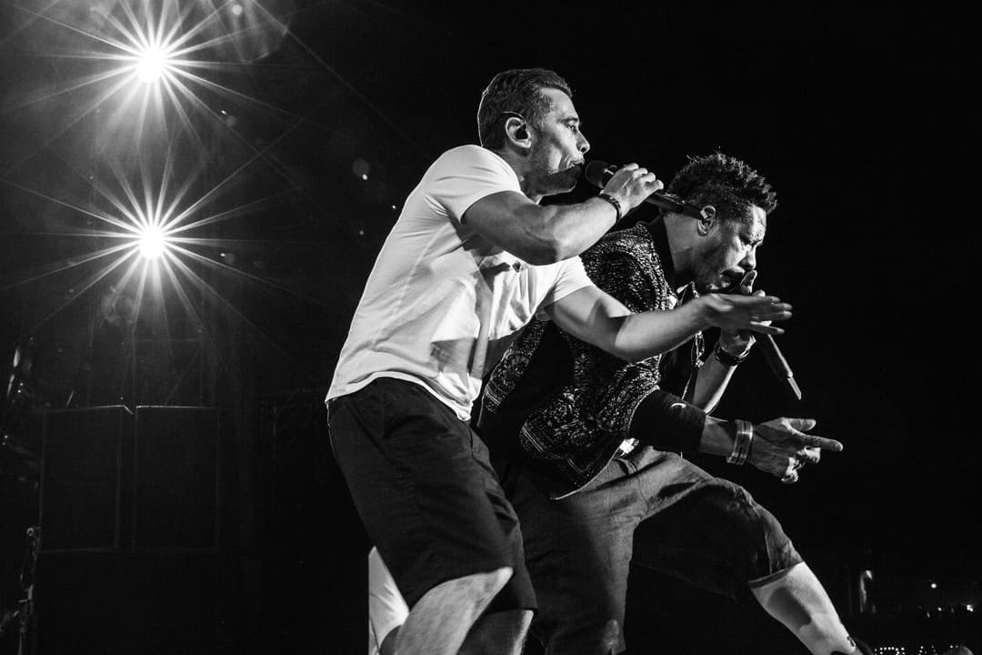 Deux rappeurs du groupe NTM en concert au Paléo Festival, chantant au micro sous les projecteurs