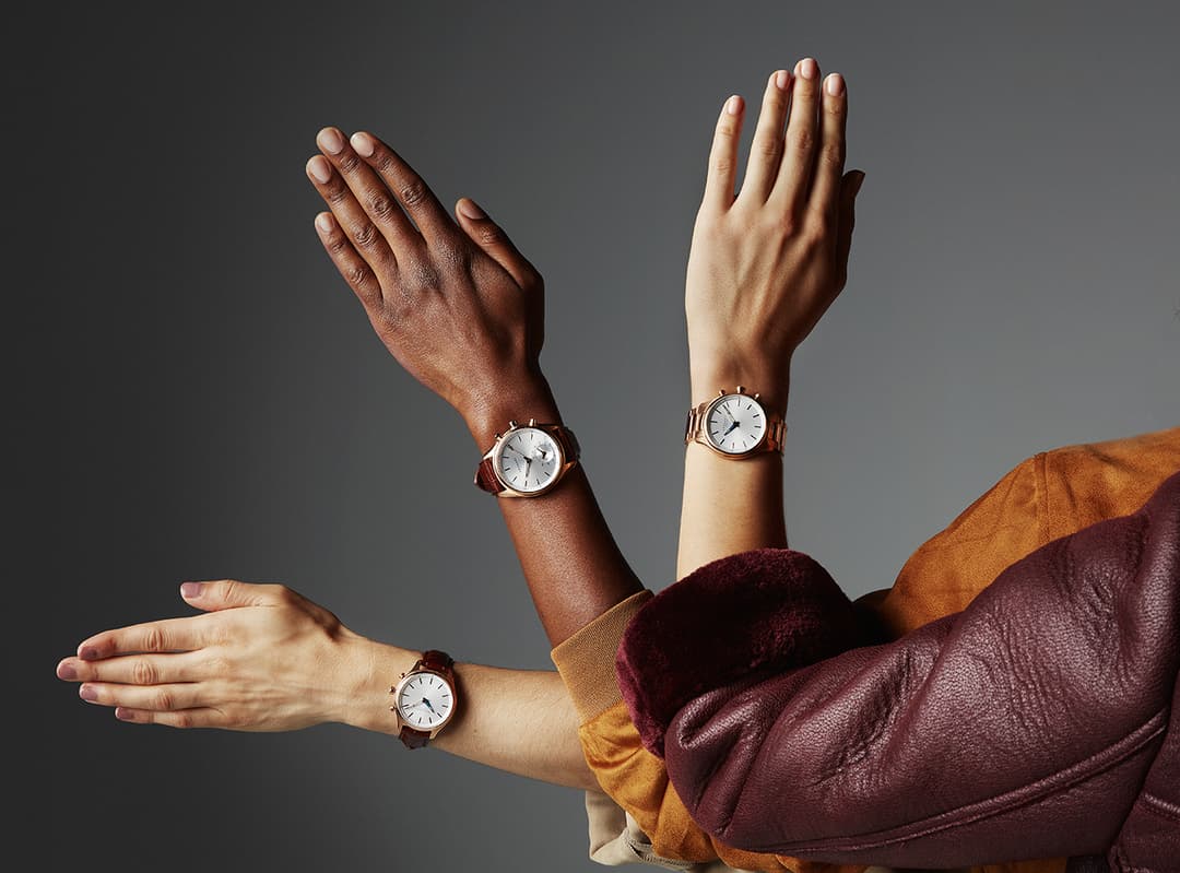 Trois montres Kronaby hybrides aux bracelets marron portées par différentes personnes, affichant un cadran blanc épuré