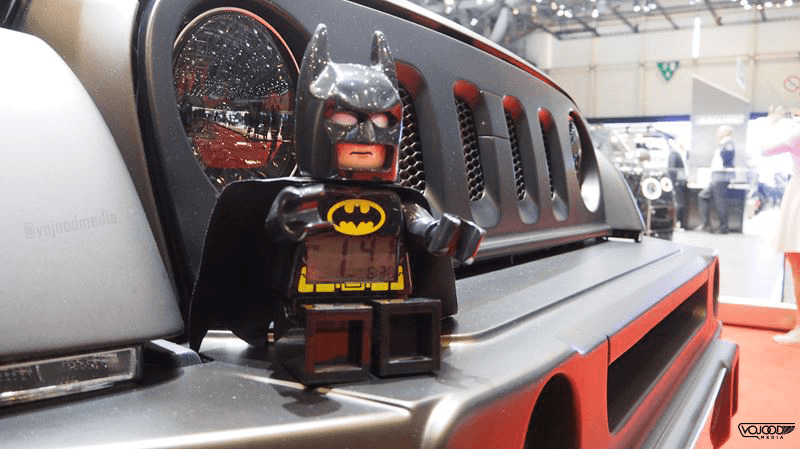 Figurine Lego Batman posée sur le tableau de bord d'une voiture de sport rouge au Salon de l'Automobile de Genève