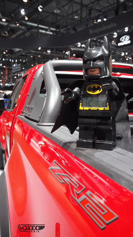 Figurine Batman en costume noir assis dans une Chevrolet Camaro rouge au Salon International de l'Automobile de Genève