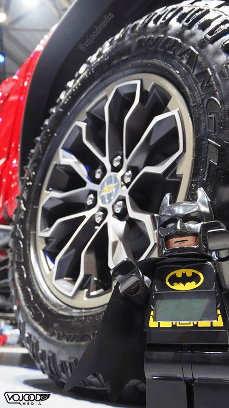 Figurine Lego Batman posée devant la roue d'une Chevrolet Camaro rouge au Salon de l'Automobile de Genève