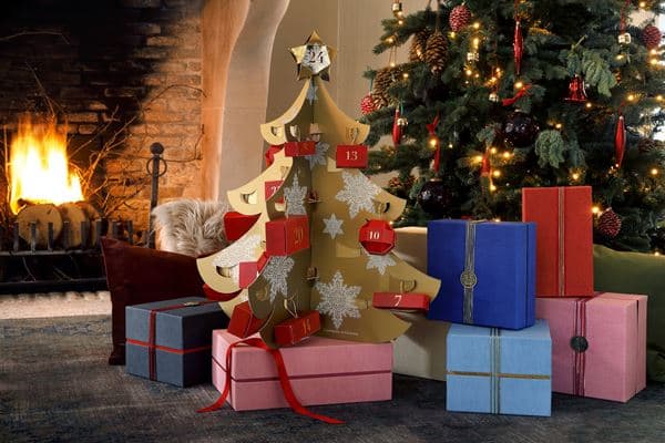Calendrier de l'Avent Rituals 2017 en forme de sapin avec portes numérotées, entouré de cadeaux colorés devant une cheminée