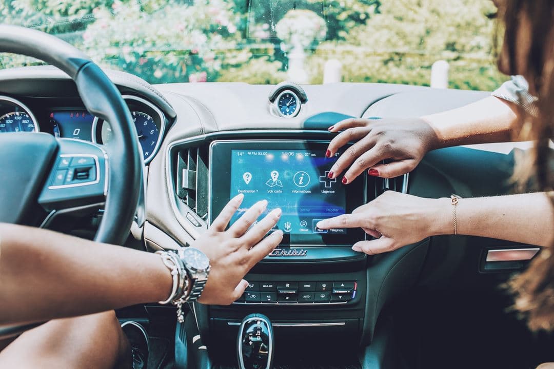 Intérieur d'une Maserati, deux femmes manipulent l'écran tactile du système d'infodivertissement