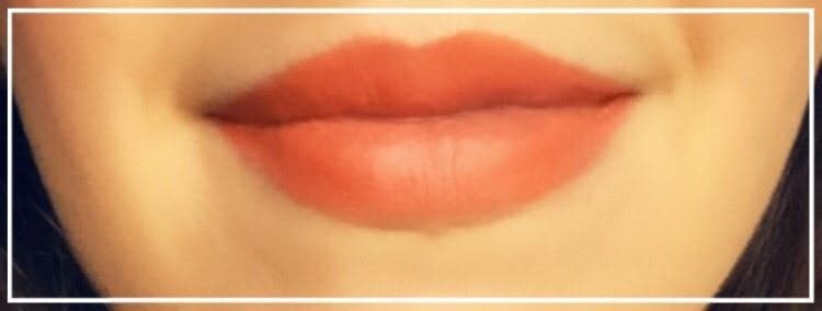 Lèvres portant un Balm Stain Wet n Wild de couleur rouge-orange avec effet teinté