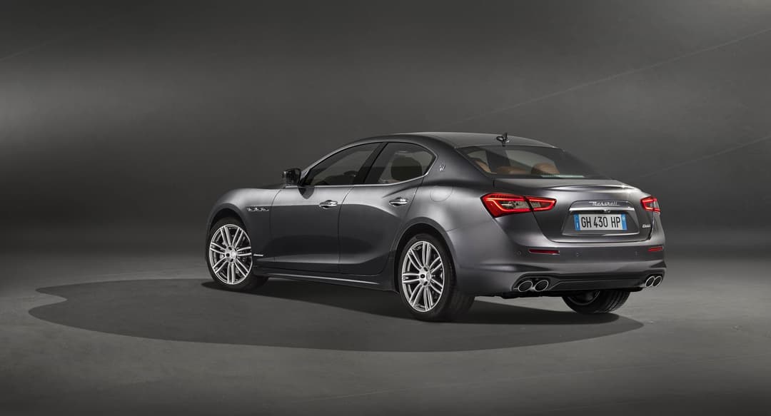 Maserati Ghibli GranLusso gris métallisé en trois-quarts arrière, projecteurs LED allumés, sur fond neutre