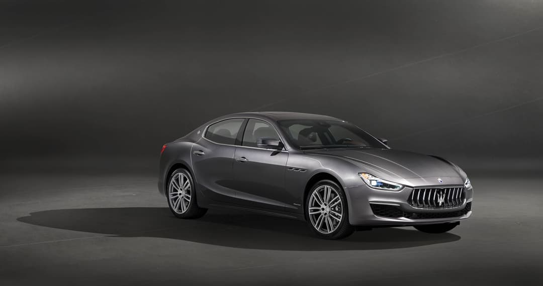 Maserati Ghibli GranLusso berline grise avec éclairage avant caractéristique, vue de profil sur fond neutre