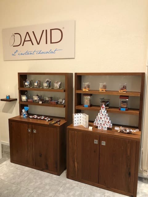 Devanture de la boutique David l'Instant Chocolat avec enseigne murale et vitrines en bois exposant des produits chocolatés