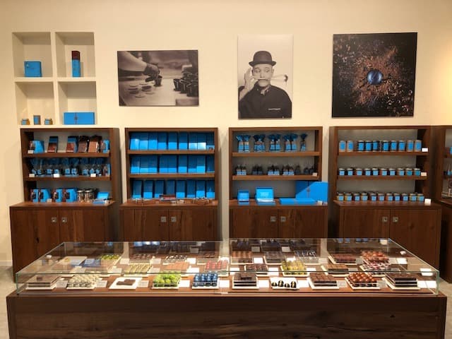 Boutique David l'Instant Chocolat avec vitrines marron et bleu contenant des créations chocolatées, photos et portrait du créateur au mur