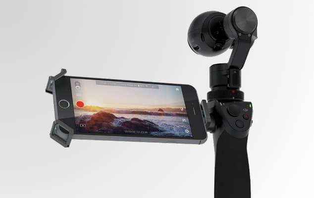 DJI Osmo, stabilisateur à cardan noir avec smartphone attaché affichant un paysage de montagne au coucher de soleil