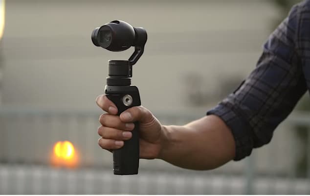 DJI Osmo tenue en main, caméra noire avec capteur orienté vers l'avant, poignée ergonomique visible
