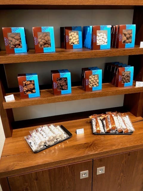 Étagère en bois présentant des boîtes de chocolats enrobés aux fruits secs et des plateaux de dégustations de pralines
