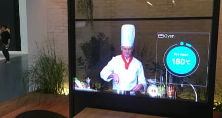 Écran tactile transparent affichant un chef cuisinier et des contrôles de four numériques en temps réel