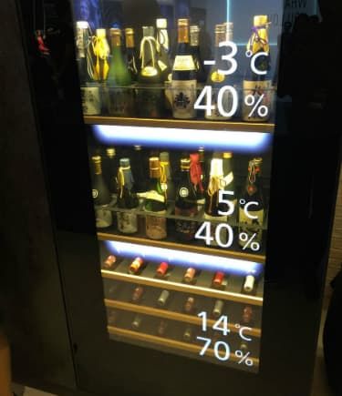 Écran OLED transparent de 55 pouces affichant les caractéristiques d'une cave à vin avec températures et taux d'humidité