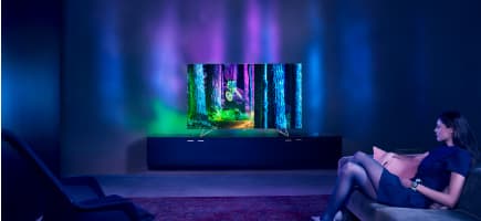 Téléviseur 65 pouces en UHD affichant une image colorée, entouré d'un halo lumineux projetant la lumière sur le mur