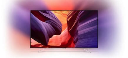 Téléviseur Samsung affichant une image de canyon aux couleurs violettes et oranges intenses, avec technologie Ambilight projetant des halos lumineux autour de l'écran