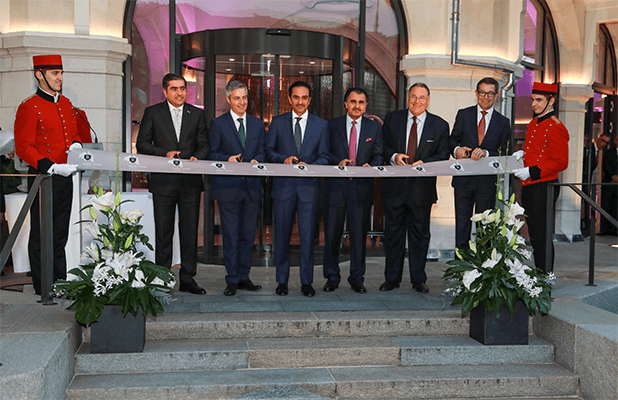 Cérémonie d'inauguration du Royal Savoy Lausanne avec autorités et huissiers en costumes traditionnels découpant un ruban