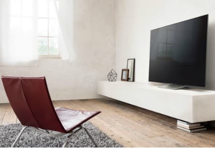 Sony XD94 4K HDR montée sur meuble blanc dans un salon minimaliste avec fauteuil rouge