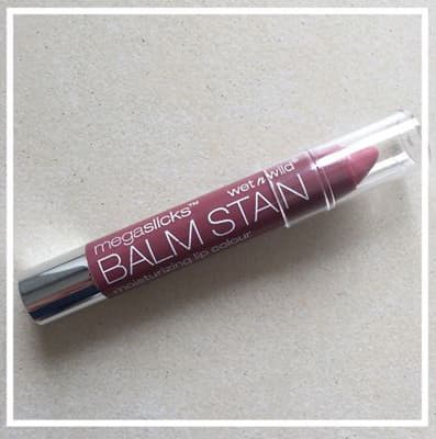 Balm Stain Wet N Wild de couleur rose mauve, tube applicateur ouvert sur fond beige